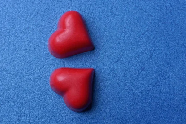 Zwei Rote Herzen Aus Süßigkeiten Liegen Auf Einem Blauen Tisch — Stockfoto