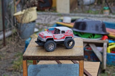 Eski renkli plastik bir araba caddedeki kahverengi ahşap bir masada duruyor.