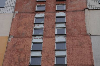 Caddedeki büyük bir evin kahverengi beton duvarındaki sıra sıra eski pencere.