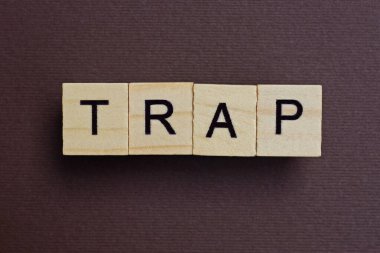 Kahverengi bir masanın üzerindeki küçük tahta harflerden gri kelime tuzağı.