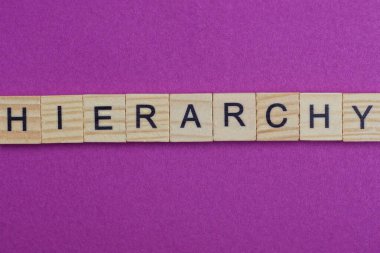 Ahşap harflerden oluşan kelime hiyerarşisi kırmızı arka planda yatıyor. 