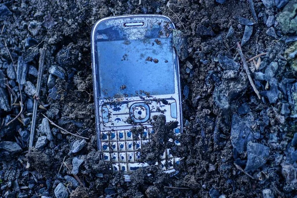 灰色の古い携帯電話が通りの黒い大地にあり — ストック写真