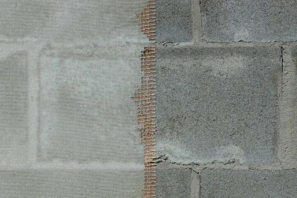 Gri beton duvar ve tuğlaların üzerindeki kırmızı plastik ağın dokusu