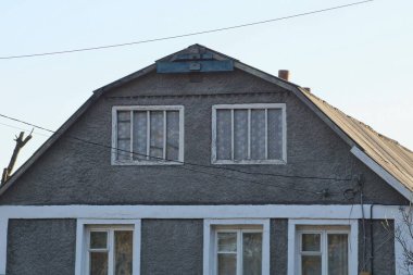 Mavi gökyüzüne karşı beyaz pencereli gri kırsal bir evin ön cephesi