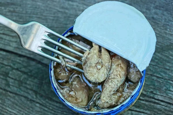 Lattina Aperta Con Pesce Sott Olio Una Forchetta Metallo Tavolo — Foto Stock