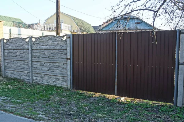 big brown metal gate and fence on a rural street