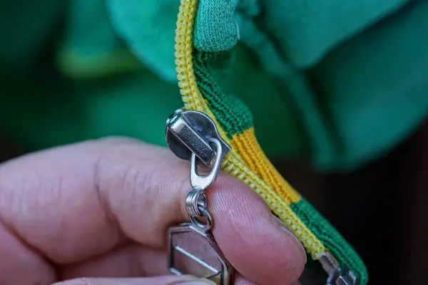 Dedos Segurar Zíper Metal Cinza Tecido Verde Amarelo Roupa — Fotografia de Stock