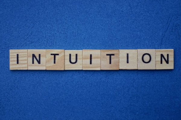 текст из интуиции слова из деревянных маленьких букв на темно-синем фоне
