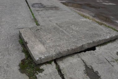Caddede asfalt yolun kenarında büyük gri bir beton levha var.