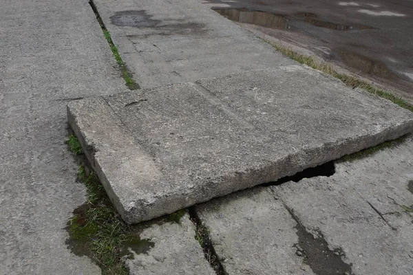 one large gray concrete slab lies on the street by an asphalt road