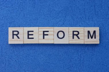 Küçük ahşap harflerin gri kelime reformu mavi bir masada yatıyor.