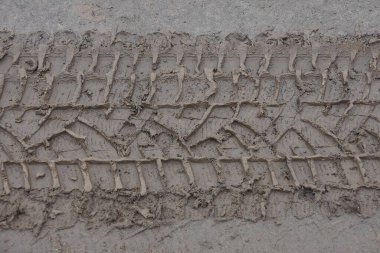 Yoldaki ıslak kil ve zeminden oluşan bir araba izinden gri kahverengi doku.