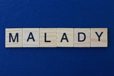  Koyu mavi arka planda siyah yazı tipi olan küçük kare ahşap harflerle hastalıklı gri kelime.