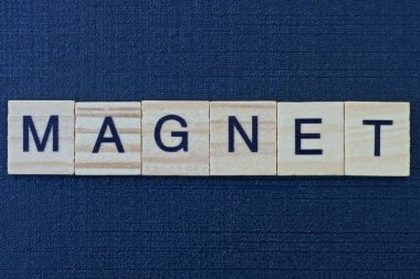  Siyah bir masanın üzerindeki gri tahta harflerden mıknatıs kelimesine mesaj at.