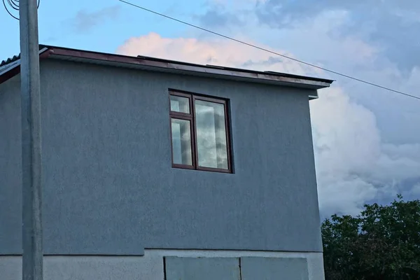 空に対する民家の灰色のコンクリートの壁にある茶色の窓です — ストック写真
