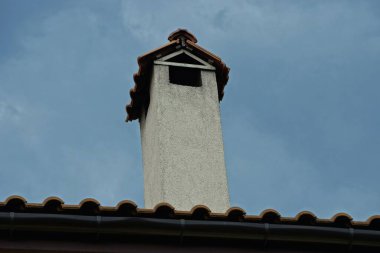 Çatıda gri gökyüzüne karşı uzun, gri bir baca.