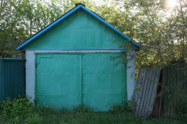 Metal kapılı ve sokakta çitleri olan eski beyaz bir garaj.