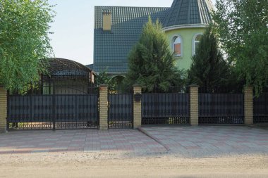 Sokakta kaldırımda siyah dövmeli gri metal kapı ve çit var.