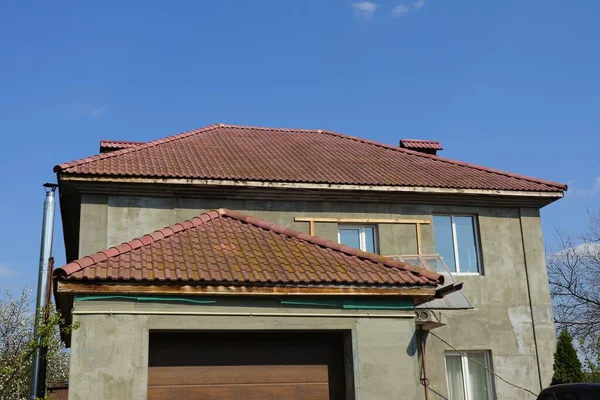 青い空に対して茶色のタイル張りの屋根の下に窓のあるグレーの家 — ストック写真