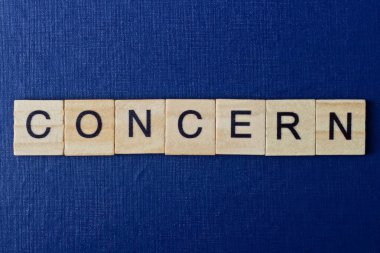  Mavi arka planda siyah yazı tipi olan küçük kare tahta harflerle ilgili gri kelime endişesi