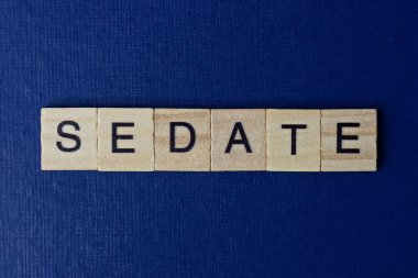 mavi arkaplanda siyah yazı tipi olan küçük kare tahta harflerle sakinleştir