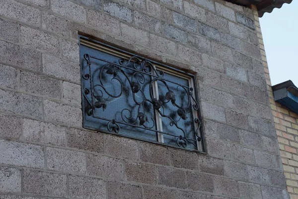 Jedno Małe Okno Czarną Żelazną Kratą Kutą Szarej Ceglanej Ścianie — Zdjęcie stockowe
