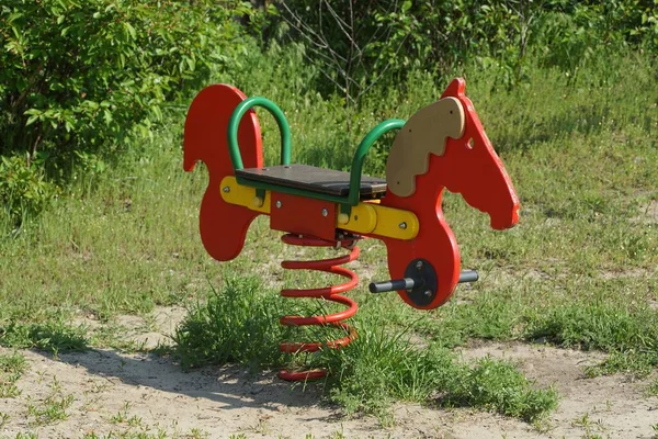 Ένα Παιδικό Κούνημα Από Ένα Κόκκινο Ξύλινο Άλογο Μια Σιδερένια — Φωτογραφία Αρχείου