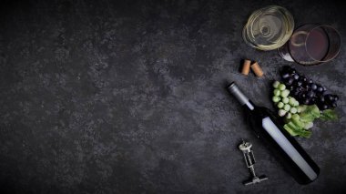 Şarap şişesi ve aksesuarlar karanlık zeminde.