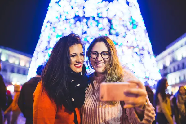 Dvě holky se fotí vedle vánočních světel. Užívali si společně v Madridu. — Stock fotografie