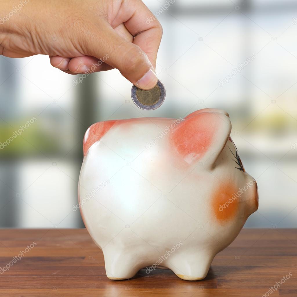 Businessman putting coin into piggy bank