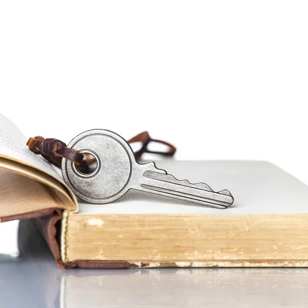 Schlüssel und altes Buch auf weißem Hintergrund — Stockfoto