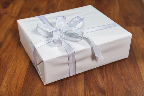 Caja de regalo blanca sobre fondo de madera — Foto de Stock