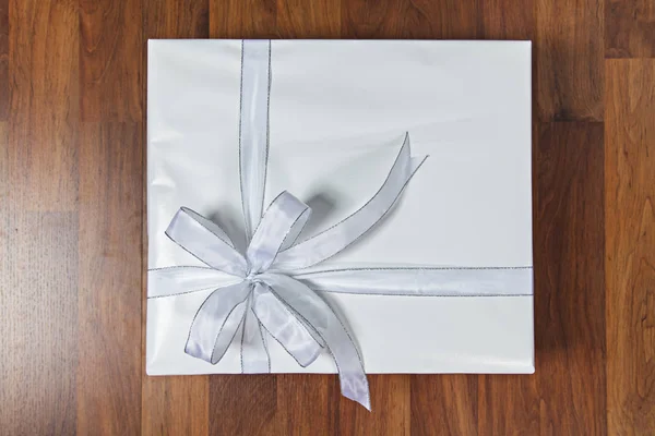 Caja de regalo blanca sobre fondo de madera — Foto de Stock