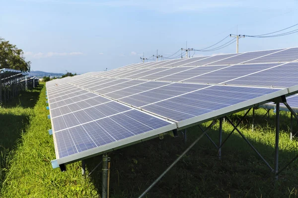 Solpaneler på grönt fält, solkraftverk — Stockfoto