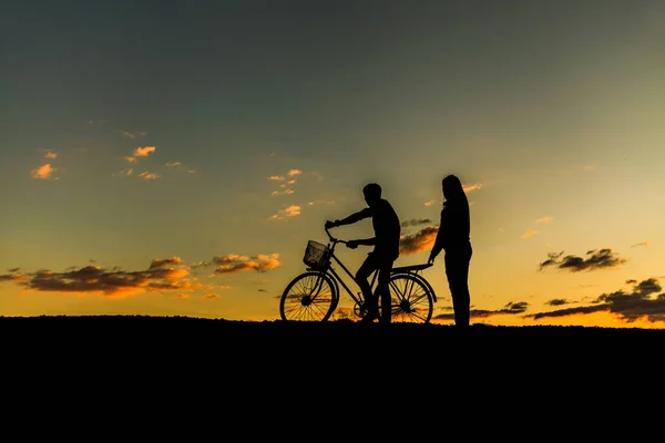 Σιλουέτα του γλυκό ζευγάρι στην αγάπη χαρούμενη ώρα και ποδηλάτων στην bea — Φωτογραφία Αρχείου