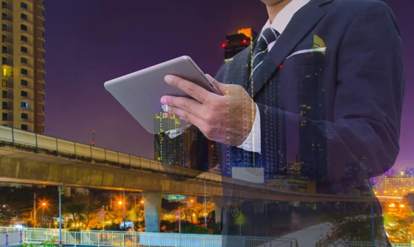 Double exposure of businessman using digital tablet with modern