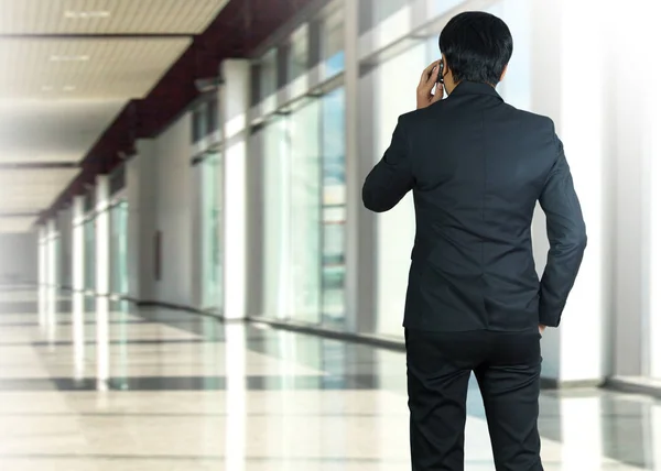 Atractivo hombre de negocios usando un teléfono celular en una oficina moderna —  Fotos de Stock