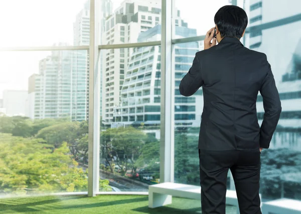 Привлекательный бизнесмен, пользующийся мобильным телефоном в современном офисе — стоковое фото