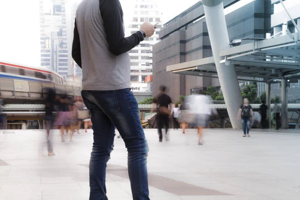 Man met de telefoon met mensen lopen in beweging vervagen — Stockfoto