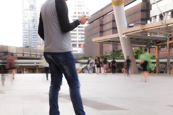 Man holding the phone with People walking in motion blur — Stock Photo, Image