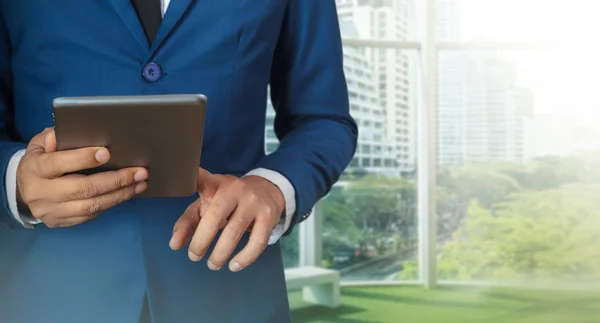 Бизнесмен с использованием цифрового планшета с современным зданием — стоковое фото