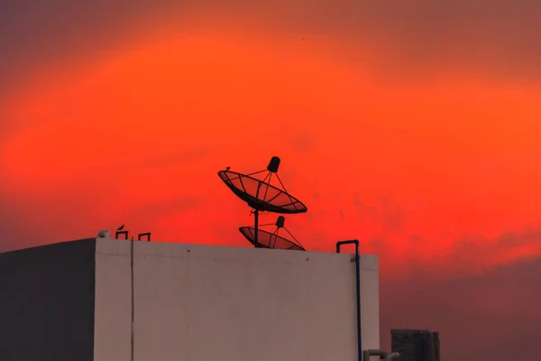 都市の夕暮れ空に衛星放送受信アンテナ — ストック写真