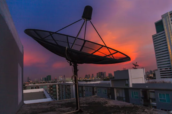 都市の夕暮れ空に衛星放送受信アンテナ — ストック写真