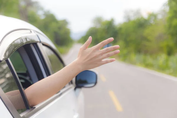 Femme main à la fenêtre de la voiture sur une route de campagne — Photo