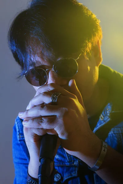 Um homem cantando em um microfone sob holofotes com fumaça em um — Fotografia de Stock