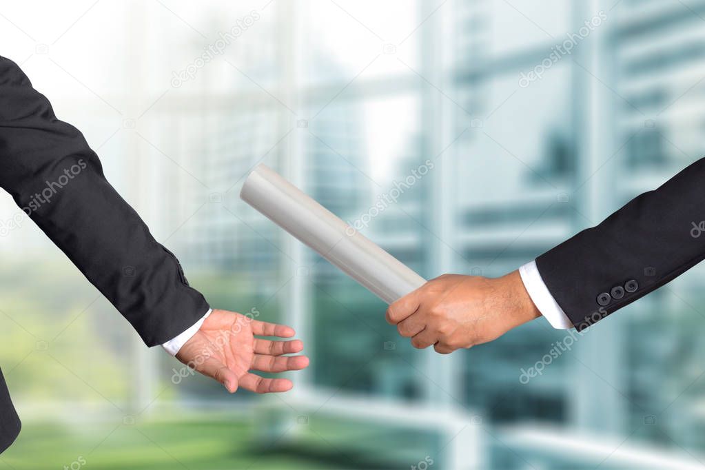 Cropped hand of businessman passing relay baton to colleague