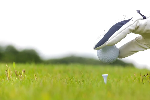 Hand met golfbal met tee op golfbaan — Stockfoto
