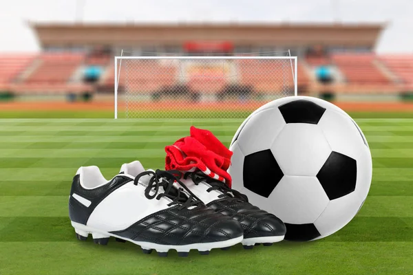 Zapatos de fútbol y pelota de fútbol en el campo de fútbol — Foto de Stock