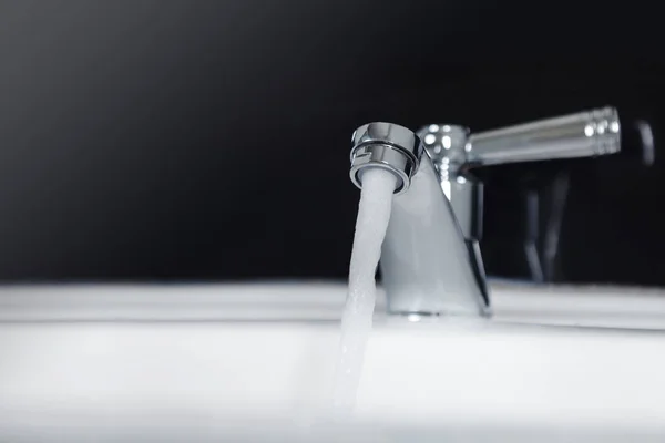 Кран и поток воды в ванной комнате — стоковое фото