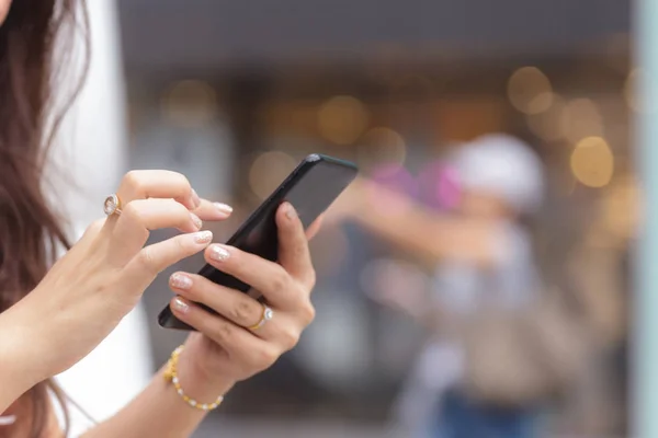 Primer plano de las manos de la mujer sosteniendo el teléfono inteligente con backgro borroso —  Fotos de Stock